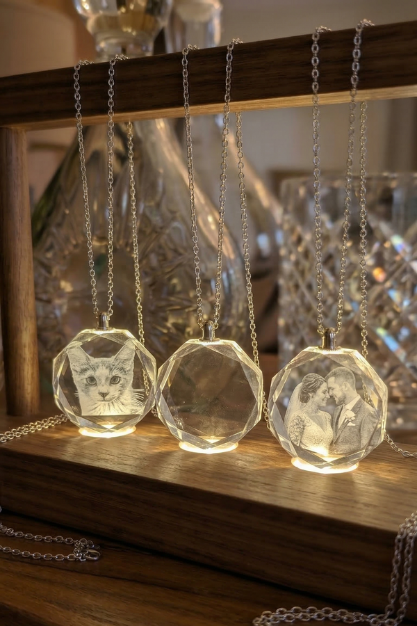 Clear crystal pendants with engraved designs on a wooden stand