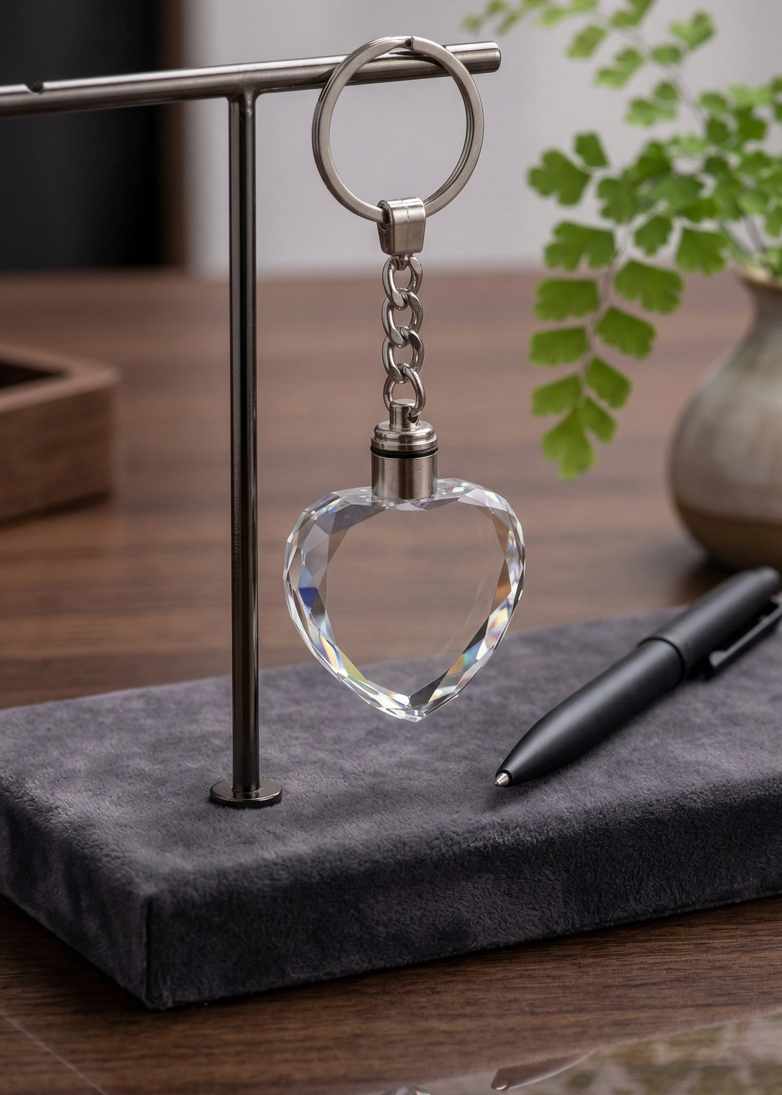 Crystal heart keychain on a stand with a pen and plant in the background