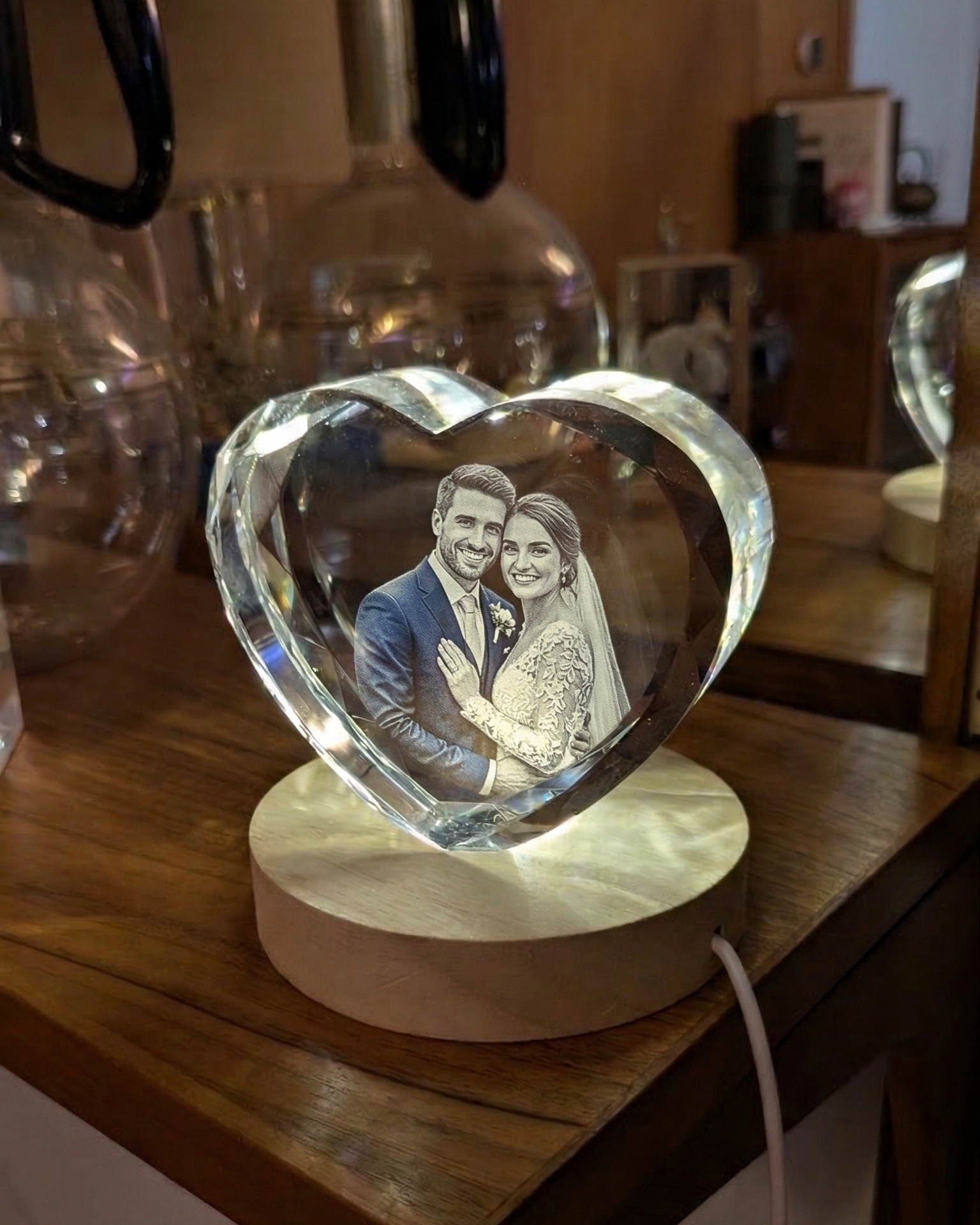 Heart-shaped crystal with engraved photo of a couple on a wooden surface.
