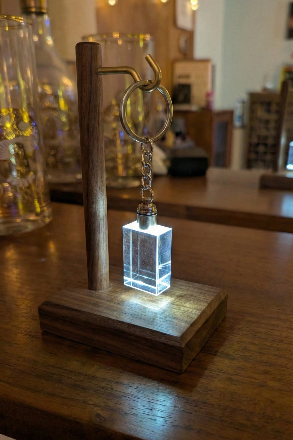 Keychain with a small square light on a wooden stand on a wooden surface.