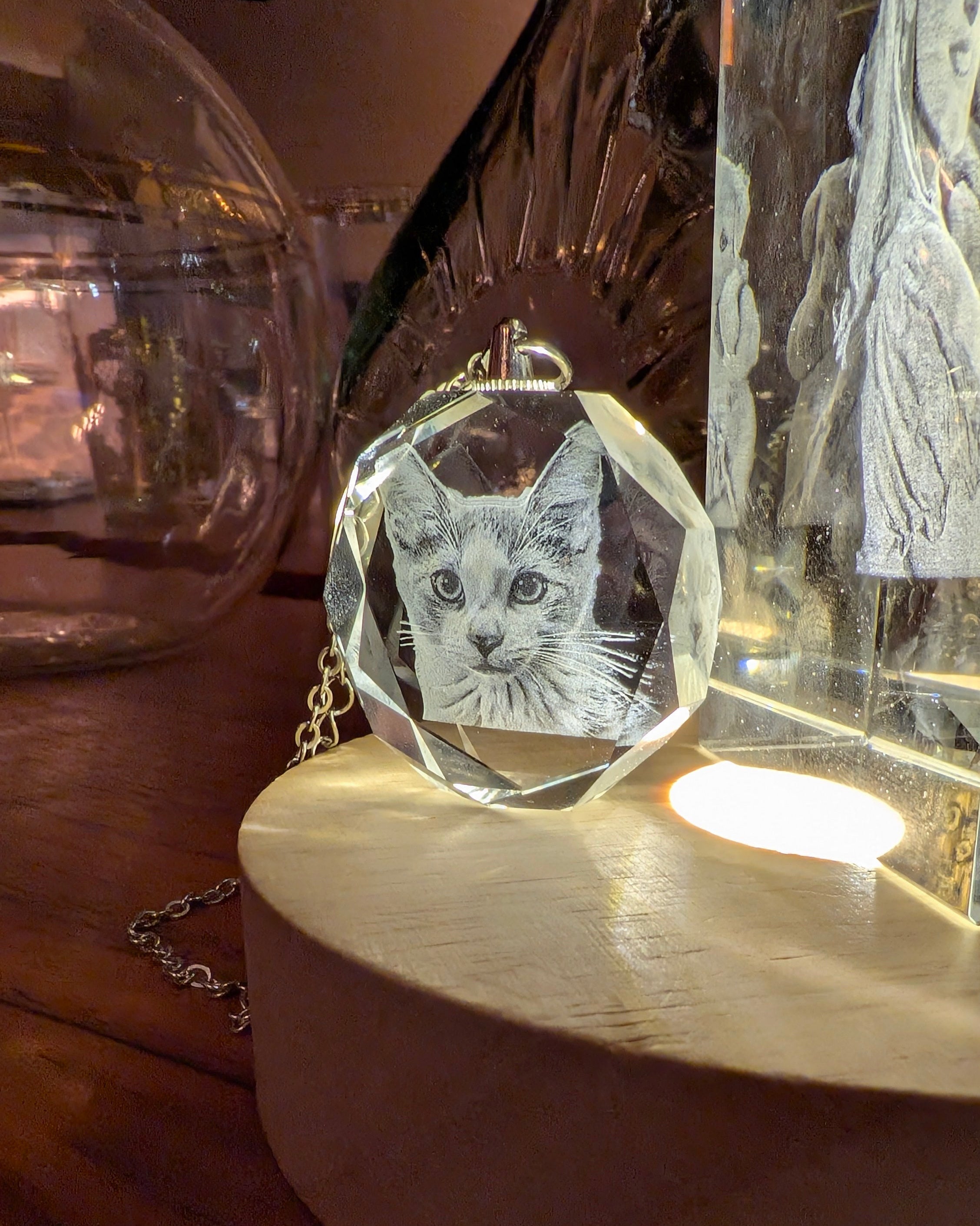 Crystal pendant with engraved cat design on a wooden surface