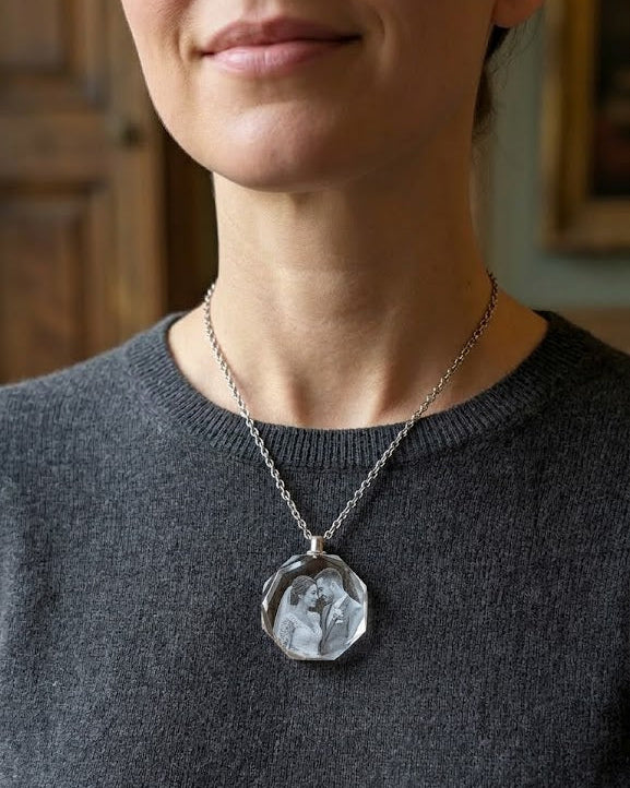Person wearing a dark gray sweater with a necklace featuring a large, clear pendant.